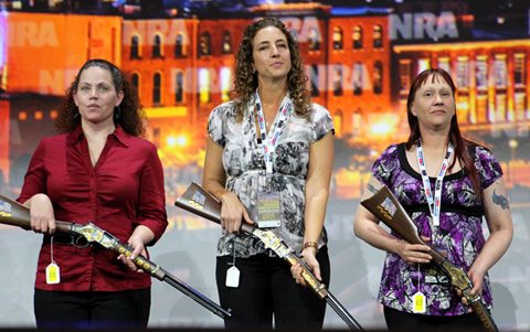 People on stage at the NRA Foundation Banquet, with rifles and tactical gear