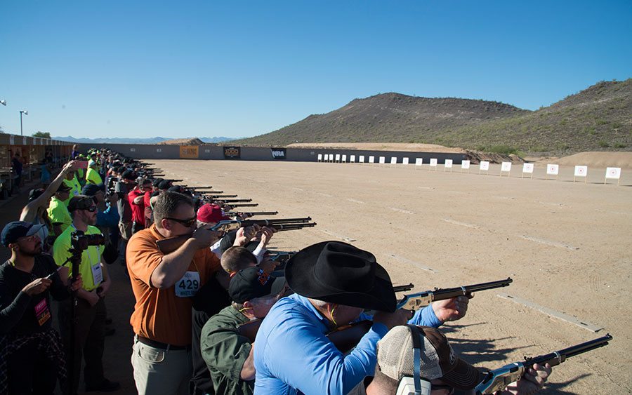 Large group of people firing rifles at outdoor shooting range