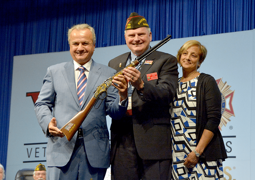 Military service officer receives Henry Repeating Arms rifle award on stage at VFW convention