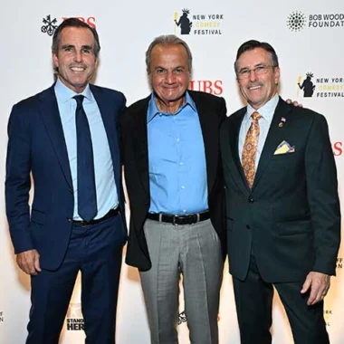 Three men in formal suits posing together at an event