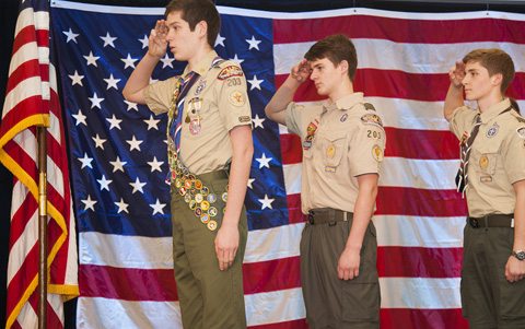 Boy Scout leaders standing in front of American flag with Henry rifles