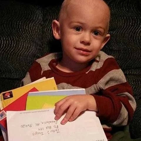 Young boy in red and white striped sweater holding envelope with handwritten address