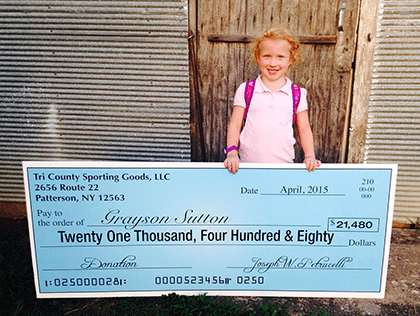 Young girl holding large check from Henry Repeating Arms Company