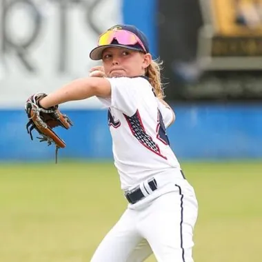 Young baseball player in uniform and gear catching a ball on a field